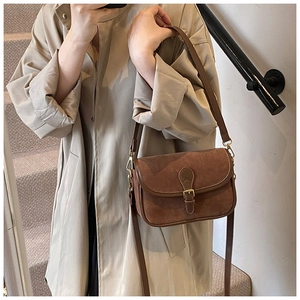Detail of vintage brown frosted texture saddle bag with golden buckle and adjustable strap