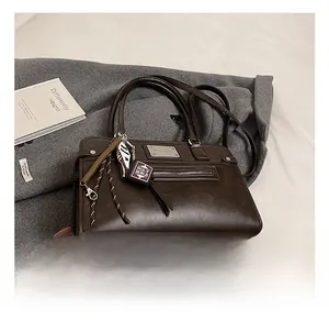 Detail view of vintage brown oil wax leather shoulder bag with zipper and Bible pendant