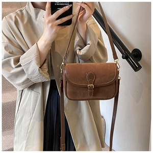 Close-up of brown matte saddle bag with vintage gold buckle and adjustable strap