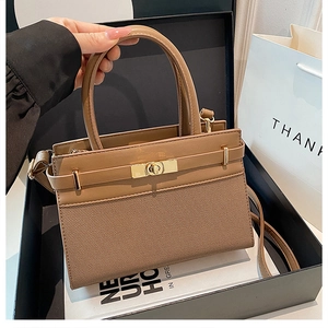 Close-up of khaki handbag featuring woven texture, gold twist lock, and gift packaging