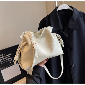 Vue détaillée du sac bourse crème en cuir grainé avec cordon de serrage et logo doré
