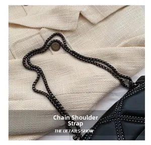 Detail of black leather shoulder bag with silver rivet patterns and metal chain strap
