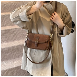 Detail of a brown matte suede crossbody bag with vintage gold buckle and leather trim