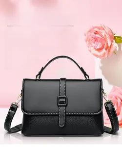 Detail of black leather messenger bag featuring white stitching and square buckle design