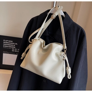 Détail du sac seau crème avec cordon, texture en cuir grainé et garnitures métalliques