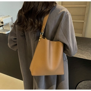 Close-up of caramel lychee grain leather tote bag with metal rivet detail on the side