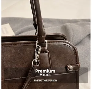 Detail shot of the vintage silver metal hook and leather texture on the brown shoulder bag