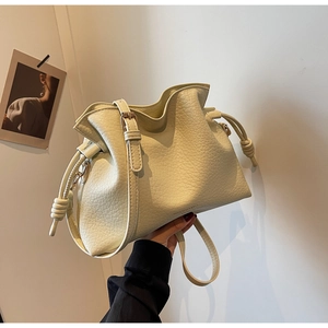 Détail du sac seau crème avec cordon de serrage, texture cuir et bandoulière réglable
