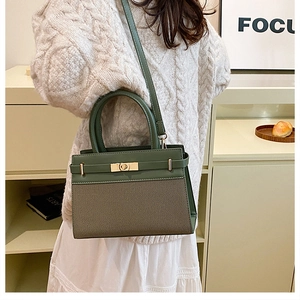 Detail of green leather and khaki canvas patchwork handbag with golden metal hardware