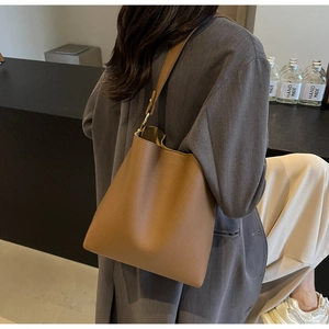 Detail of brown lychee grain leather tote bag with adjustable strap and gold metal buckle