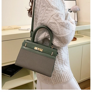 Detail of dark green canvas tote with gold hardware and leather strap on a model