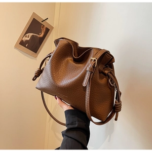 Gros plan du sac seau en cuir marron grainé avec cordon de serrage et bandoulière