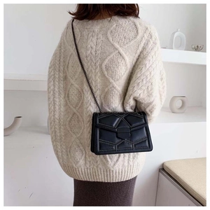 Rear view of a model wearing the black quilted crossbody bag with stud detail and chain
