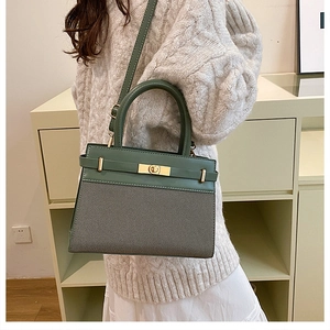 Detail of dark green leather and grey twill fabric handbag with gold turn-lock buckle
