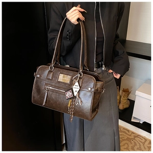 Close-up of vintage brown leather bag with cross charms and metal logo details
