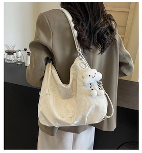 Detailed view of white marble patterned tote bag with a soft cloud plush pendant charm