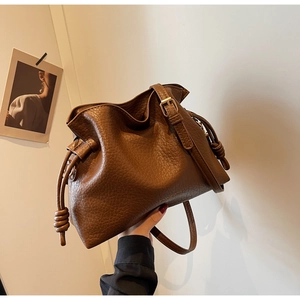 Détail du sac seau marron à cordon avec texture grainée et finitions dorées