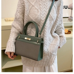 Detail of green crossbody bag with textured fabric and golden clasp held by a model