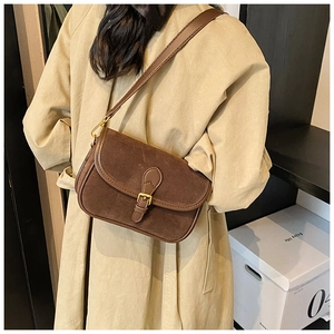 Close-up of a vintage brown crossbody bag with matte texture and gold buckle on a model