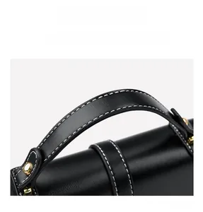 Close-up of premium black leather handle with white contrast stitching and gold hardware