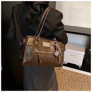 Detailed view of deep brown vintage tote bag with decorative zippers and bible charm