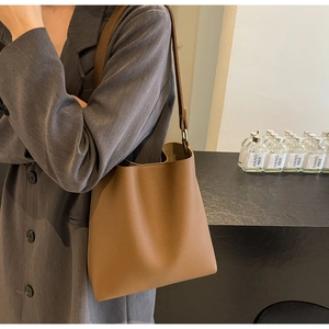 Detail of brown lychee grain leather bucket bag with metal buckle and adjustable strap