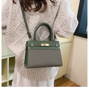 Detail of elegant dark green leather and gray fabric handbag with metal rotary clasp