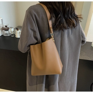 Rear view of model wearing a brown leather bucket bag with premium lychee texture