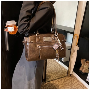 Detail of dark brown retro crossbody bag featuring unique charms and leather texture