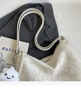 Detail view of marble texture tote bag with plush charm on a grey blazer background
