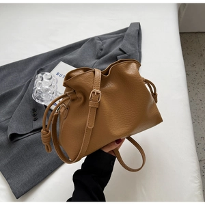 Détail du sac seau camel avec fermeture à cordon et nœuds décoratifs en similicuir grainé