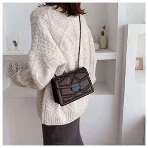 Detail view of brown quilted crossbody bag with metal rivets and black chain strap