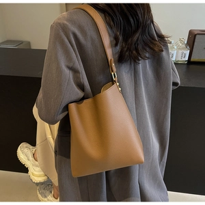 Detail of caramel lychee leather bucket bag with wide strap and gold metal hardware