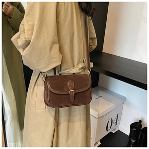 Brown frosted suede saddle bag styled with beige trench coat for a retro autumn look