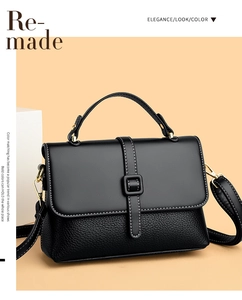 Detail of black leather satchel showing white stitching and gold-toned metal hardware