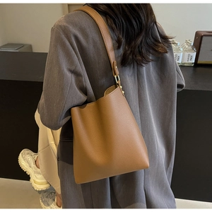 Close-up of brown lychee grain leather bucket bag with elegant gold metal hardware