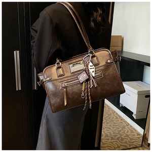 Detail of dark brown vintage faux leather handbag with metal plaque and Bible charm