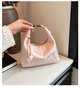 Detail of pink satin jacquard handbag with landscape patterns and pearl pendant charm