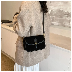 Detail of black matte leather crossbody bag with gold metal buckle and leather strap