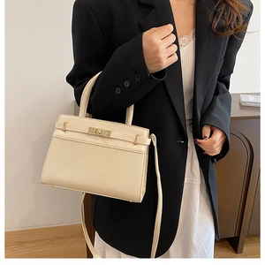 Detail of beige canvas and leather拼接 handbag with golden hardware clasp and handle