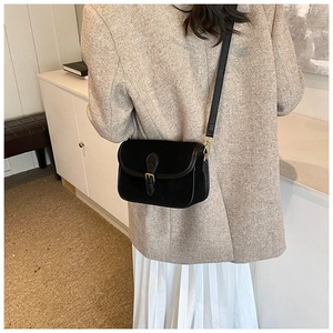 Detail of matte black square crossbody bag with gold metal buckle and leather strap texture