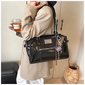 Detail of black glossy PU leather tote bag with silver chain and holy bible mini charm