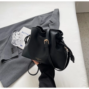 Vue détaillée du sac seau noir en cuir à motif litchi avec boucle en métal doré