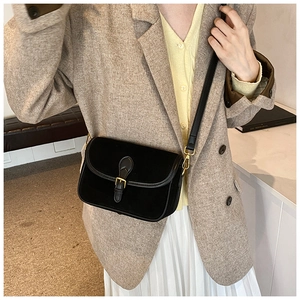 Close-up of black suede crossbody bag with elegant gold buckle and vintage texture