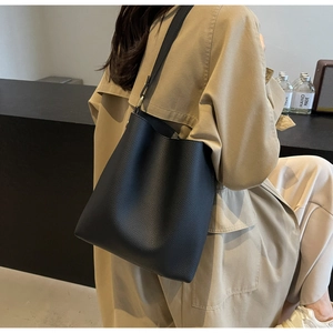 Detail of the black pebbled leather tote bag showing texture and adjustable shoulder strap