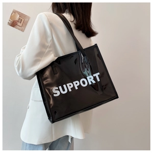 Detail of glossy black patent leather tote bag with white SUPPORT letter printing