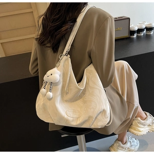 Detail view of large white marble print tote bag with plush cloud charm and long strap