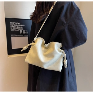 Détail d'un sac seau en cuir grainé blanc crème avec cordon et logo doré élégant