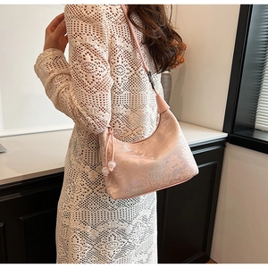 Close-up of pink jacquard handbag with classical Chinese patterns and bead pendant