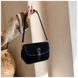 Detail showing matte suede texture and polished leather trim on black flap handbag